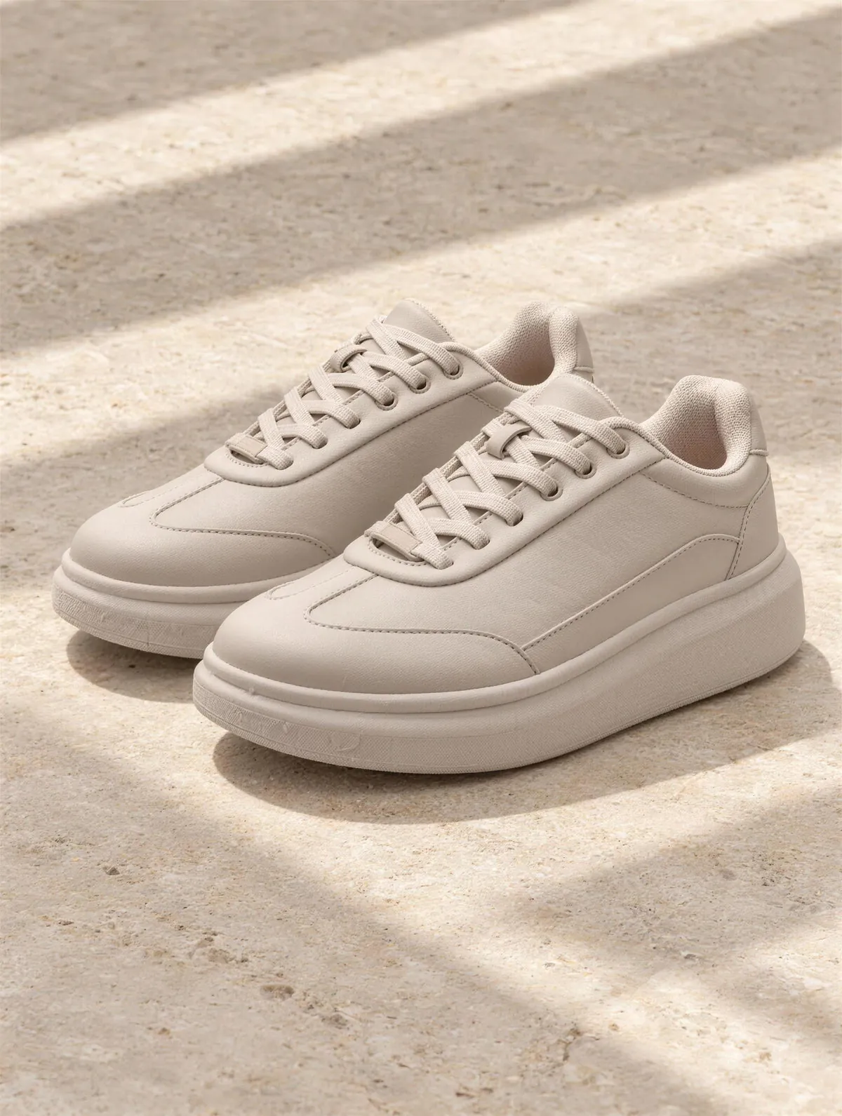 The Side Court Sneaker in greige, a pair of platform sneakers on limestone.