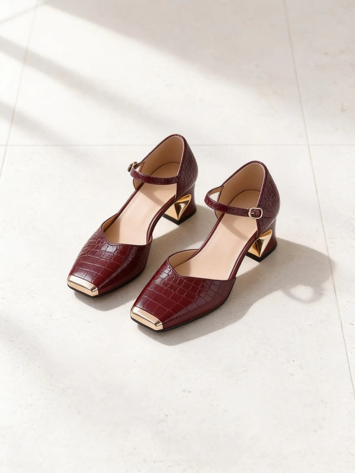 The Wine Bar Mary Jane in burgundy croc-effect leather on limestone.